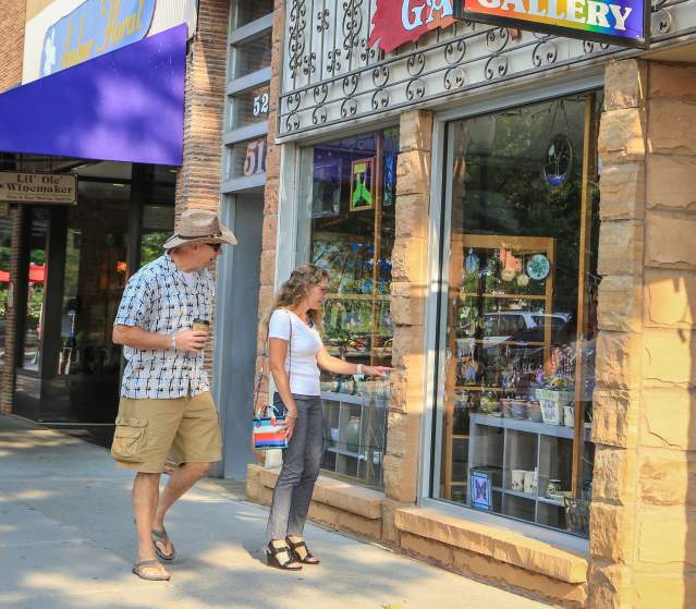 Couple walks down Main Street looking in the windows of local businesses