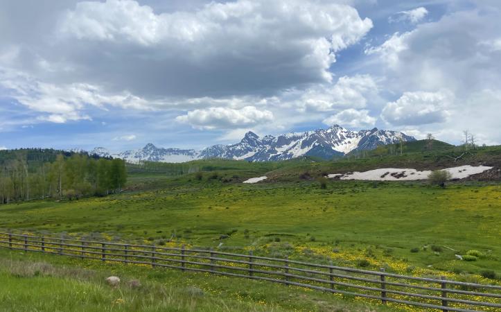 Picture of Snowy Mountains Behind Some Hills And A Fence