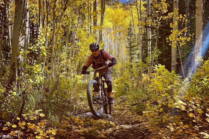 Man Biking in the fall through aspen grove