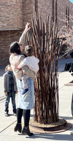 Mom holding kid while looking at Art on the Corner