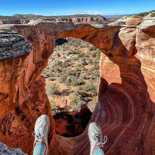 Hiker sits on top of the Cedar Tree Arch Overlook in Rattlesnake Arches