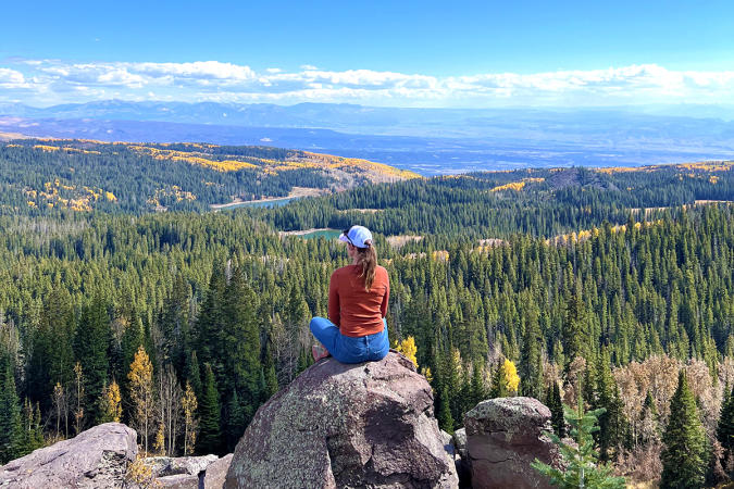 Woman Sitting on a Rock Overlooking the Grand Mesa in the Fall