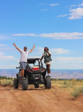Two People Standing on Wheels of a RZR