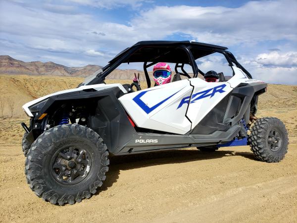 Two people sitting in a Rzr in the Desert