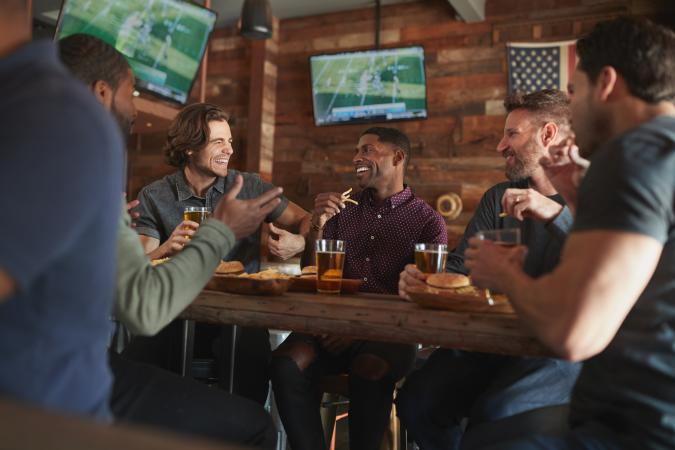 Picture of People Talking to Each Other in a Bar with a TV in the Background
