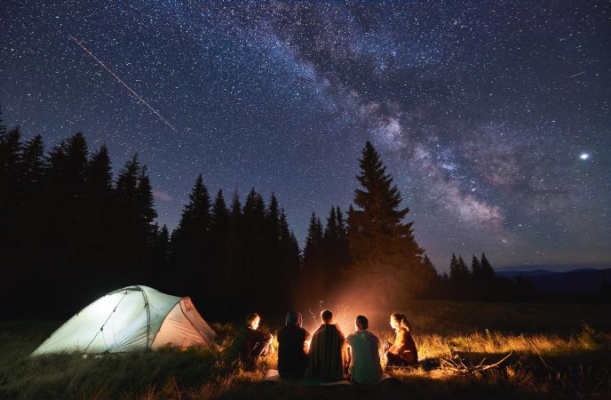 People sitting around campfire under the stars