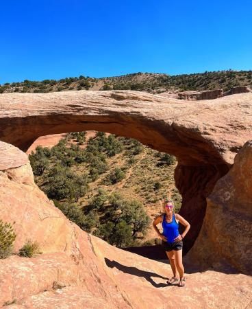 Woman Standing Above Cedar Tree Arch in Rattlesnake Canyon