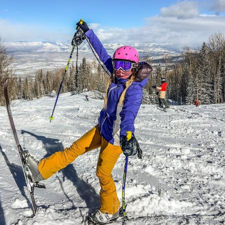 Skier Posing with one Ski up with the Ski Run in the Background